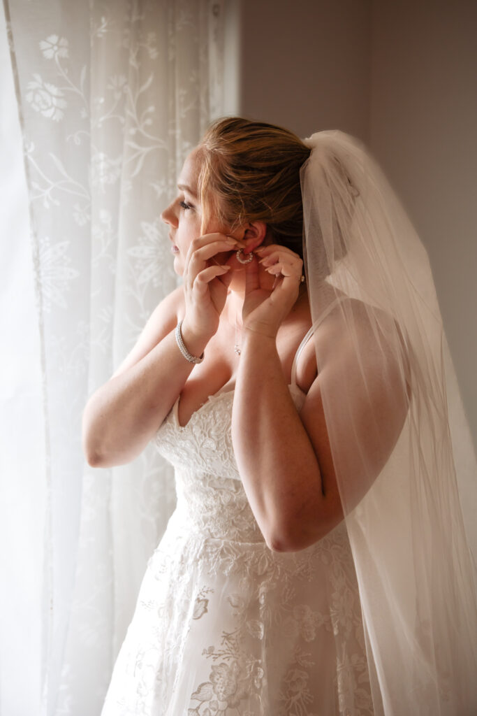 Bride wearing a white dress looking out a window