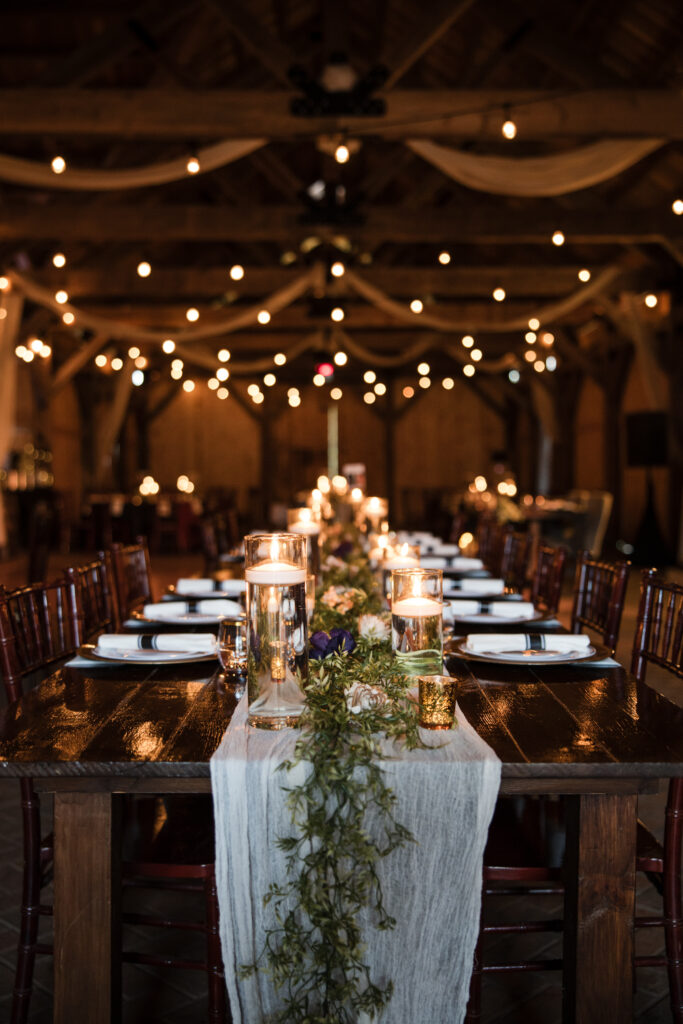 Candlelit reception tablescape with market lighting in a wooden barn