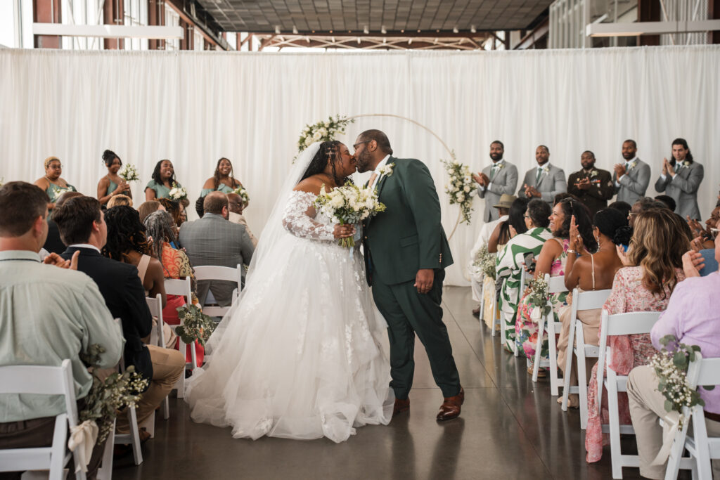 Bride and groom kissing in the middle of the aisle after being married.